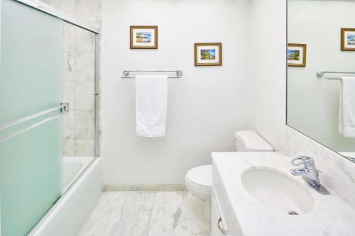 a white bathroom with a sink and a toilet at Aston at The Whaler on Kaanapali Beach in Lahaina