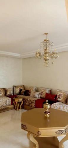 uma sala de estar com um sofá e um lustre em Appartement Résidence Panamaribo neuf em Tânger
