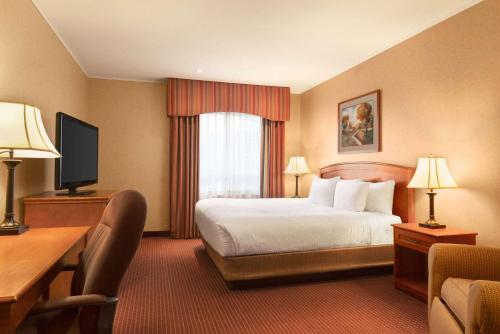 a hotel room with a bed and a desk and a television at Days Inn by Wyndham Swift Current in Swift Current