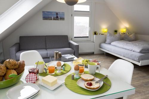Haus Nordstern Wohnung 5 في بوركوم: غرفة معيشة مع طاولة مع طعام الإفطار عليها