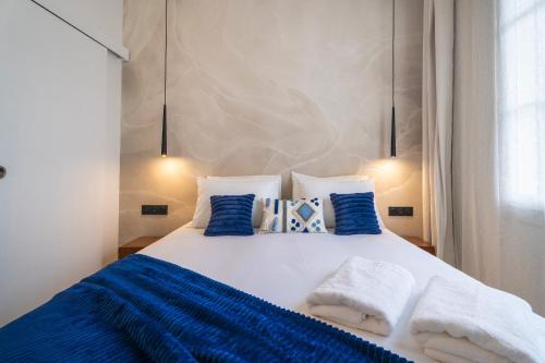 - un lit avec des couvertures et des oreillers bleus et blancs dans l'établissement L'Appart - Centre ville Plage à pied, à Sainte-Maxime