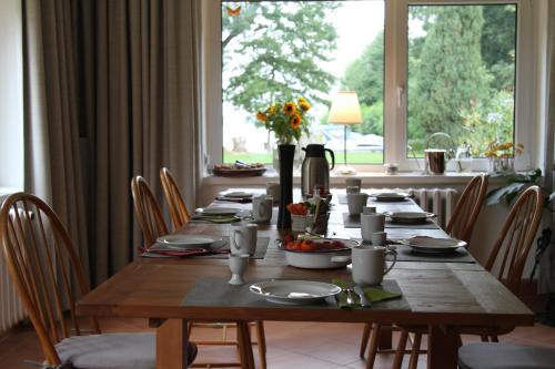 a wooden table with chairs and a large window at Landhaus Wolziger See in Görsdorf