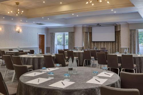 a conference room with tables and chairs and a screen at DoubleTree by Hilton St. Anne's Manor in Bracknell