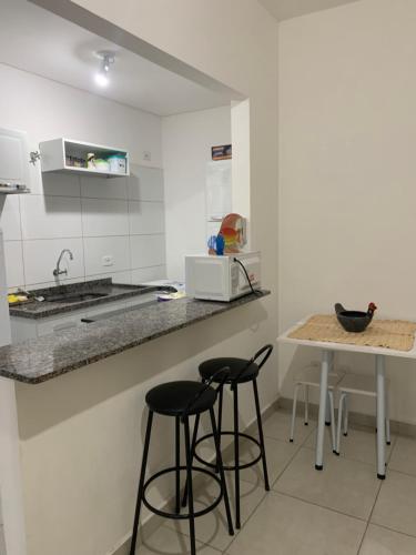 a kitchen with two bar stools and a counter at Apto em Ubatuba divisa com a Praia de Itagua e facil acesso as praias fica ao lado do Atacado Tenda na rodovia Rio Santos in Ubatuba