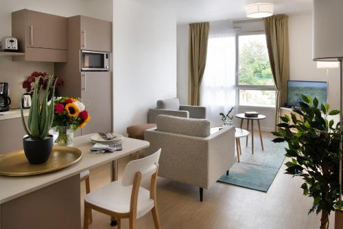 a living room with a kitchen and a living room with a table at DOMITYS - Le Solstice in Versailles