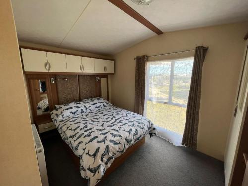 a small bedroom with a bed and a window at The Hurleys 8 Berth AV10 At Camber Sands in Camber