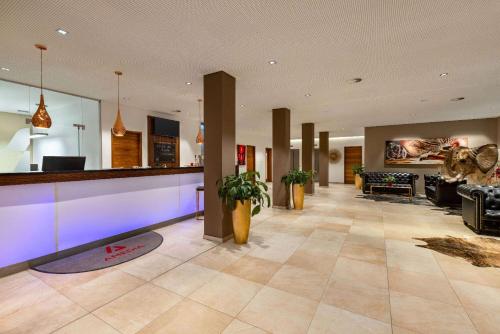 a lobby with a bar with purple lights at Amedia Plaza Dresden, Trademark Collection by Wyndham in Dresden