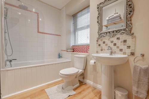 uma casa de banho com um WC, um lavatório e uma banheira em Millpond Cottage em Holmfirth