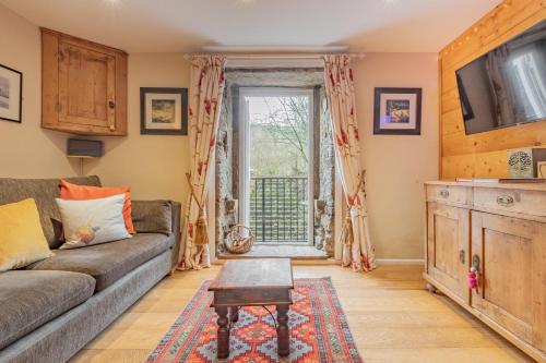 a living room with a couch and a tv at Millpond Cottage in Holmfirth