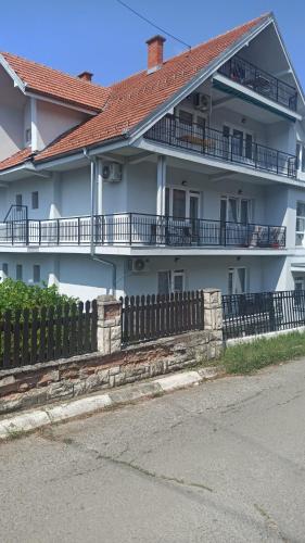 a white house with a fence in front of it at MAL Apartman in Soko Banja