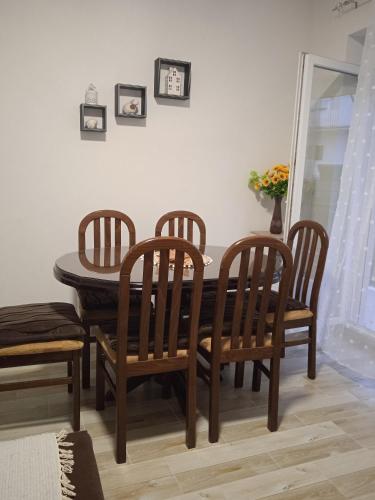 a dining room table with four chairs and a table and a mirror at MAL Apartman in Soko Banja