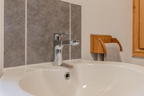 lavabo blanco con grifo en el baño en Millrace Cottage en Holmfirth