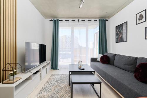 a living room with a gray couch and a tv at Fresh & Stylish Apartments in Poznań with Parking & Balcony by Renters in Poznań