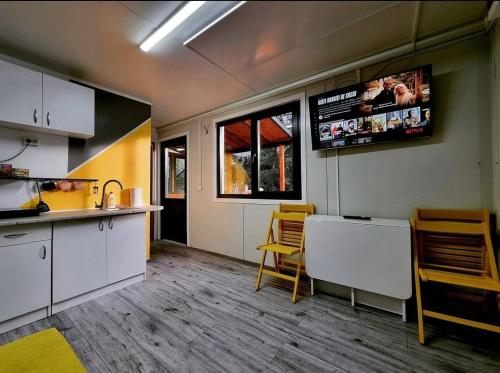 a kitchen with white cabinets and yellow chairs at Tiny House Căsuța cocoțată - Valea Doftanei - 2camere in Valea Doftanei