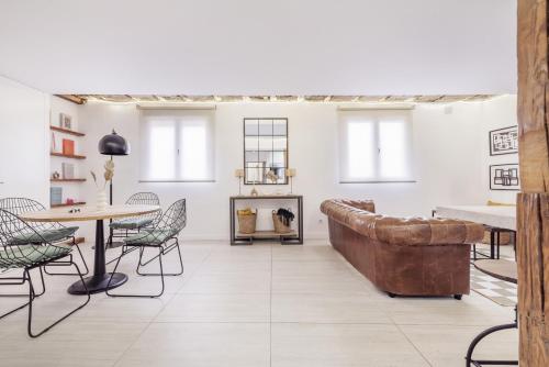 uma sala de estar com um sofá, uma mesa e cadeiras em Coqueto Ático (1B+1B) Malasaña City Centre em Madri