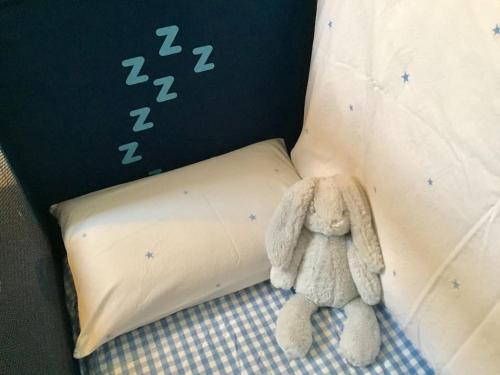 a stuffed animal sitting on a bed next to a pillow at Stylish City Centre House / 3 BR / Family Friendly in Belfast