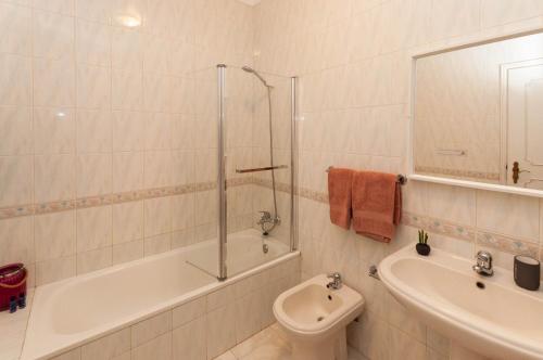 a bathroom with a tub and a sink and a toilet at Waves by OCvillas in Albufeira