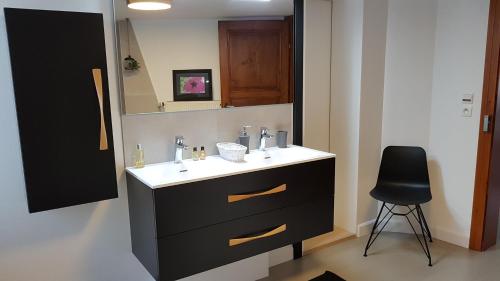 a bathroom with a sink and a mirror and a chair at LES COLOMBAGES in Zellwiller