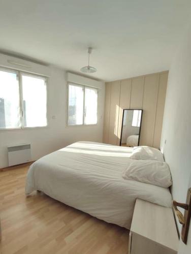 a bedroom with a large white bed and two windows at Terre de Bretagne, appartement entre port et plage in Audierne