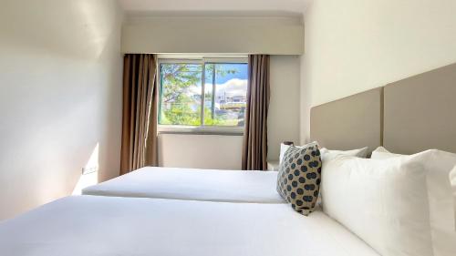 a bedroom with a white bed and a window at Villa Blue Marlin by LovelyStay in Calheta