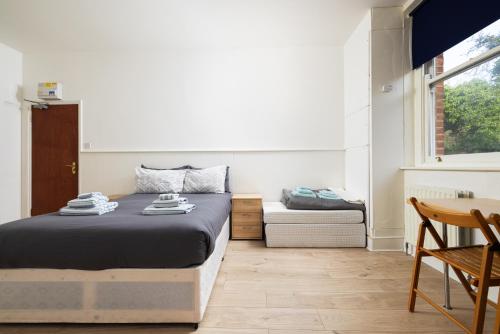 倫敦的住宿－Large Studio on Finchley Road 10，一间卧室配有一张床、一张桌子和一个窗户。
