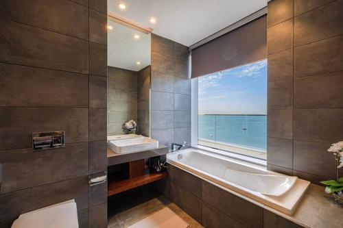 baño con 2 lavabos, bañera y ventana en Private Beach - 4BR - 8 Sleep - Pool - 180 grades Sea & Ain View - Huge Balcony - Parking - Prime Location, en Dubái