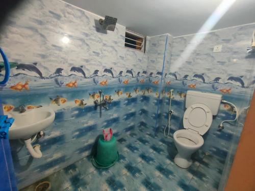 a bathroom with a toilet and a sink with fish on the wall at Pushpa Mahal A/C & Pushpa Residency in Tiruvannāmalai