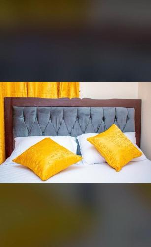a bed with two yellow pillows on top of it at Partline Apartment in Kisii