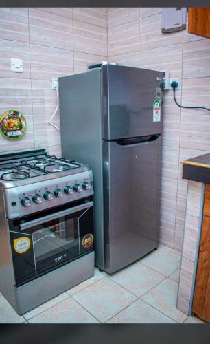 La cuisine est équipée d'un réfrigérateur et d'une cuisinière en acier inoxydable. dans l'établissement Partline Apartment, à Kisii