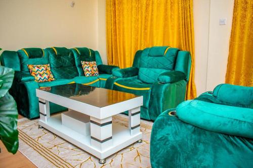 a living room with two green chairs and a table at Partline Apartment in Kisii