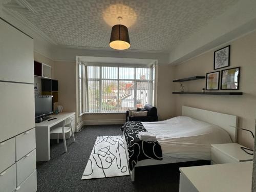 een slaapkamer met een bed, een bureau en een televisie bij Abbeyfield Guesthouse in Liverpool