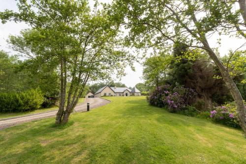 a grassy yard with trees and flowers and houses at Dromard in Kenmare