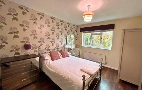 a bedroom with a bed with pink pillows and a window at Binfield - Spacious Luxurious Four Bedroom House in Bracknell