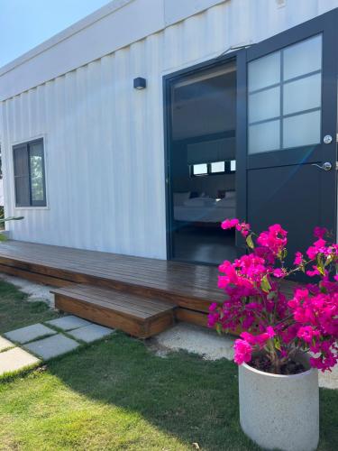 a house with a wooden porch with pink flowers at Second Hostel in Xiaoliuqiu