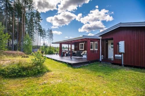 ein rotes Haus mit einer Terrasse im Hof in der Unterkunft Långrösta; Ruime blokhut grenzend aan bos in Hagfors