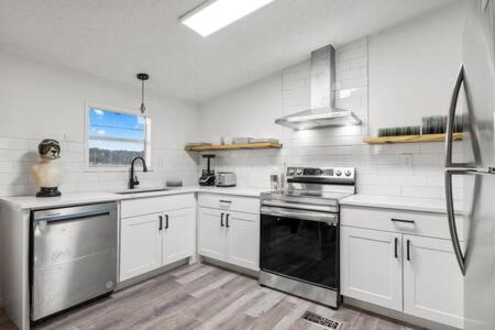 a kitchen with white cabinets and a black oven at Starlight Horizon Cabins A & B - Side-by-Side Group Retreat - Pet-Friendly Texas Hill Country Cabins Near Canyon Lake - Pool, Stargazing, Sleeps 16 in Canyon Lake