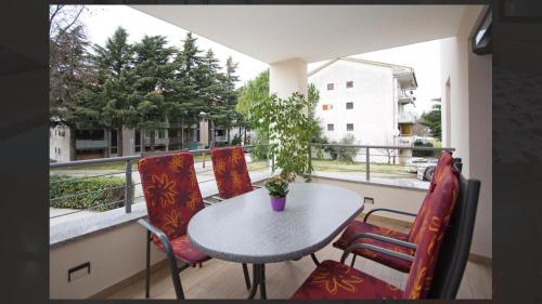 un balcón con mesa, sillas y una planta en Adria Apartments, en Poreč