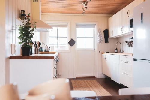 a kitchen with white cabinets and a plant on the counter at Långrösta; Ruime blokhut grenzend aan bos in Hagfors