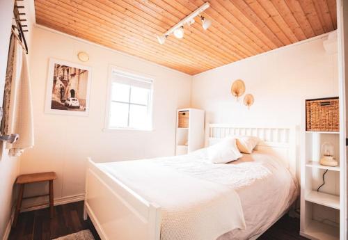 ein Schlafzimmer mit einem weißen Bett und einer Holzdecke in der Unterkunft Långrösta; Ruime blokhut grenzend aan bos in Hagfors