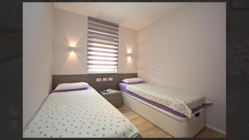 2 Betten in einem kleinen Zimmer mit Fenster in der Unterkunft Adria Apartments in Poreč