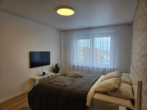 een slaapkamer met een bed en een flatscreen-tv bij Buto nuoma Žemaitės gatvėje in Telšiai