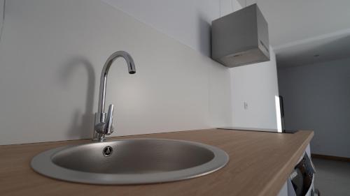 a sink with a faucet and a tv on a counter at Apartamentos Puerta de Occidente in Cornellana
