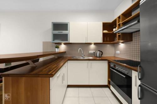 a kitchen with white cabinets and a black appliance at Apartment with cozy balcony by URBAN RENT in Kaunas