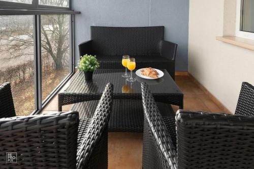 a table with a plate of food and two glasses of orange juice at Apartment with cozy balcony by URBAN RENT in Kaunas