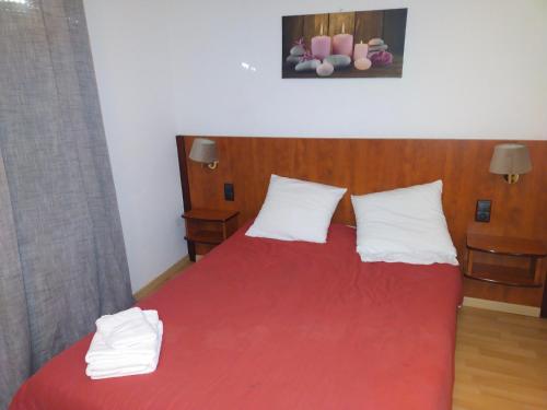 a bedroom with a red bed with two white pillows at Le Castel d'olmes in Laroque-dʼOlmes