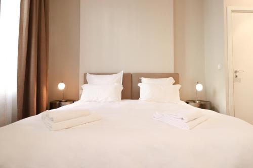 - un grand lit blanc avec 2 serviettes blanches dans l'établissement Residence Bivouac, à Cannes