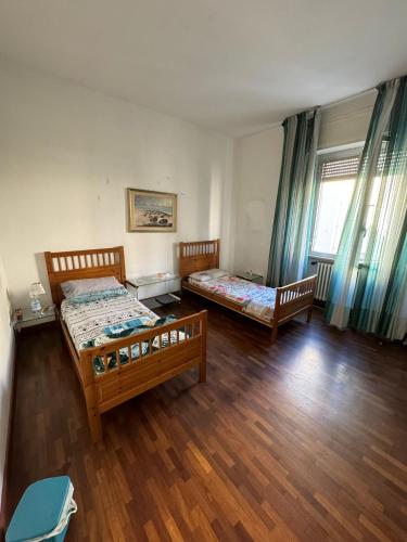 2 Betten in einem Zimmer mit Holzböden und Fenstern in der Unterkunft UrbinHouse1 in Ancona