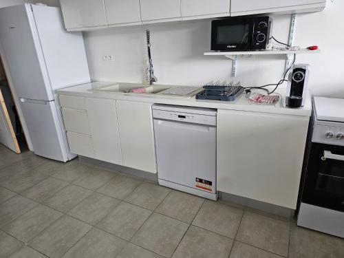 a kitchen with white cabinets and a sink and a refrigerator at CHAUDIERE DE RÊVE in Le Vauclin