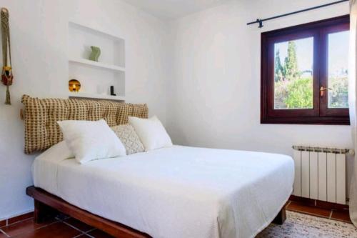 a white bed in a room with a window at Authentic 4BR Pool & Sauna Villa, Sant Agusti in San Antonio Bay