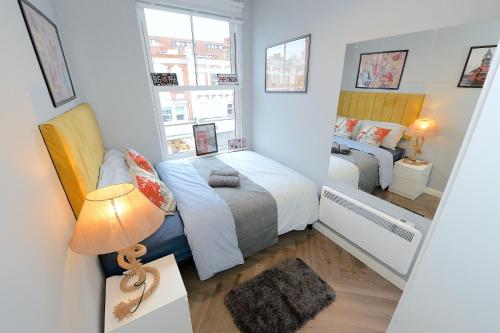 a small bedroom with two beds and a lamp at 2 BED TERRACED FLAT PICCADILLY LINE in London